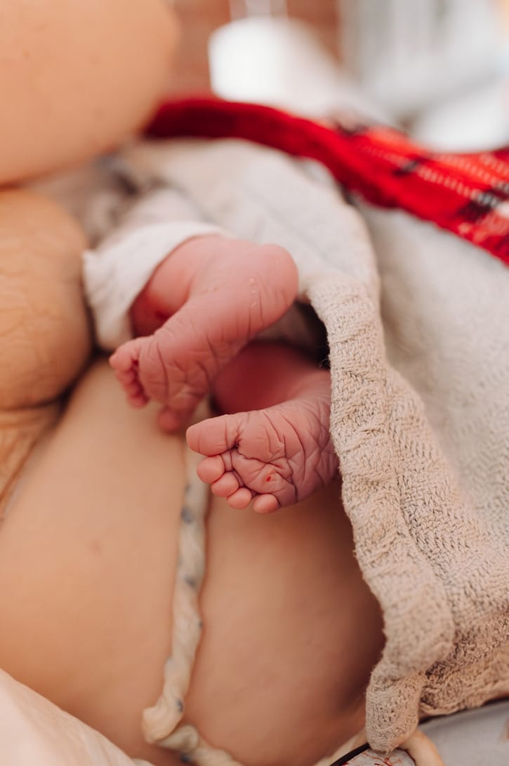 Noworodek na rękach mamy chwilę po narodzinach w domu — reportaż z porodu domowego