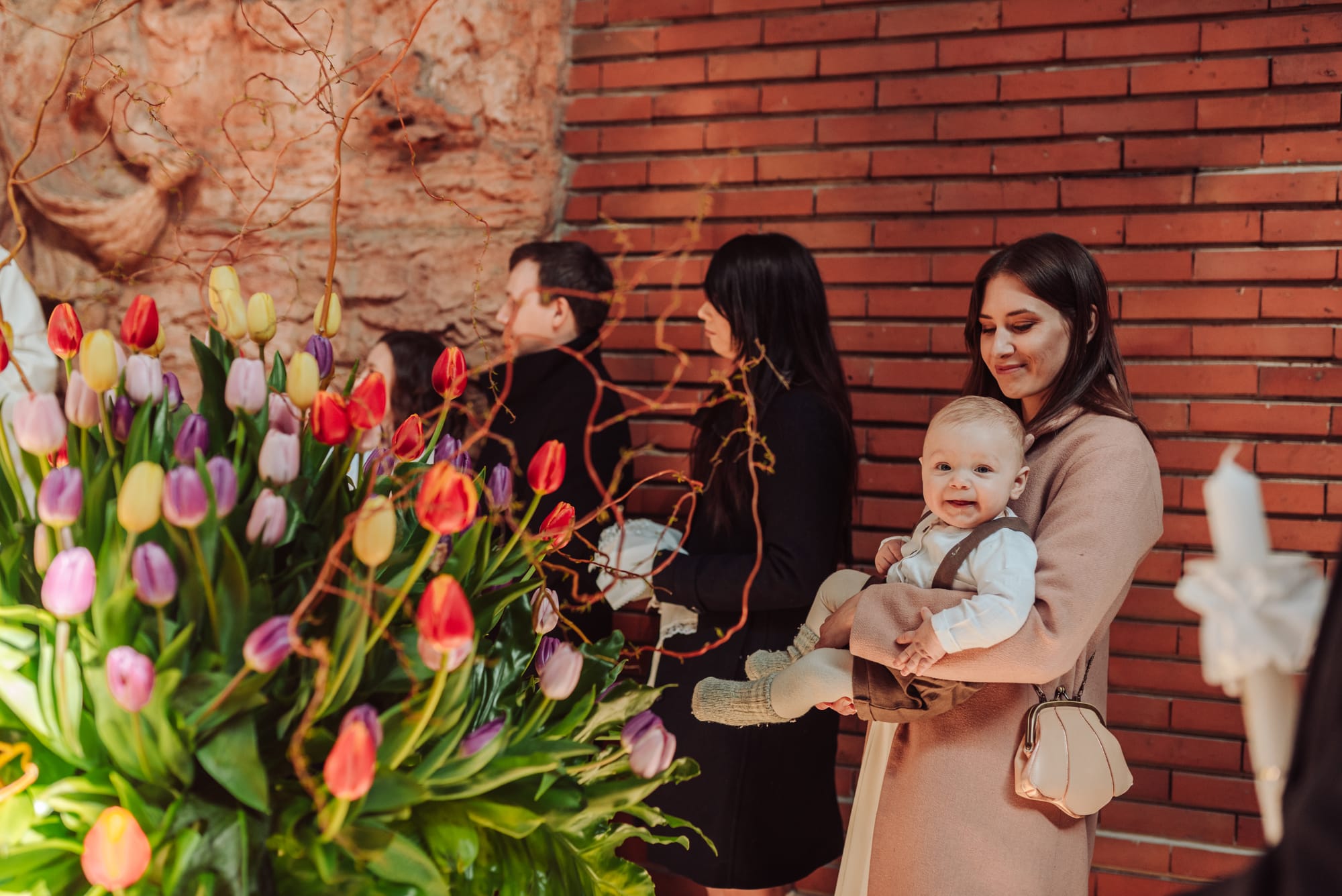 Chłopiec na rękach u roześmianej mamy podczas chrzcin w kościele — Gdańsk