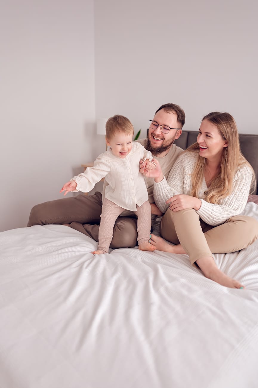 Rodzice z córką na łóżku sesja rodzinna w domu