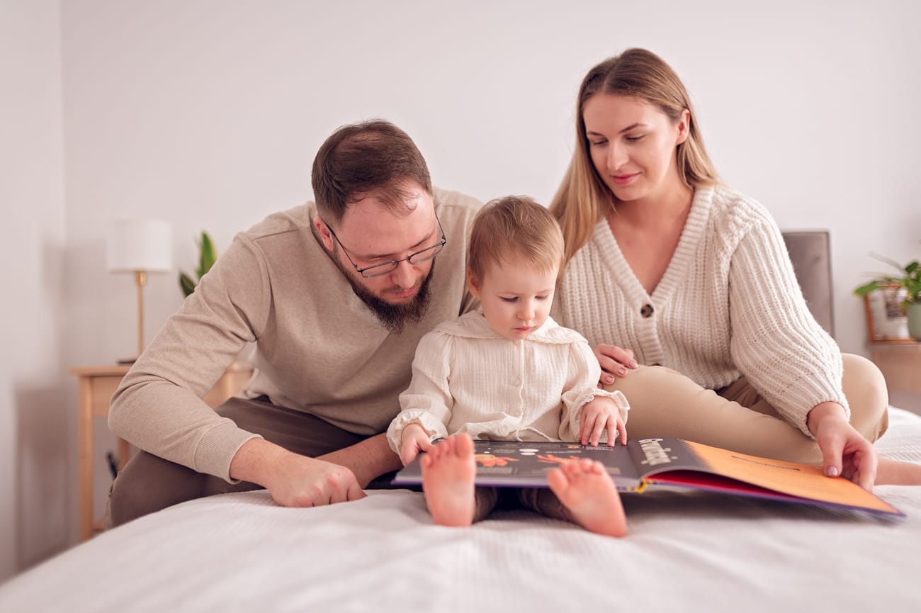 Rodzice czytają książeczkę z córką sesja w domu