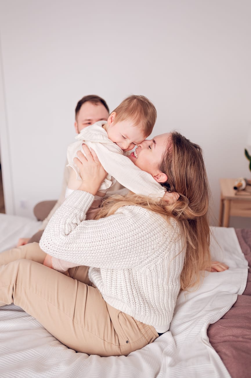 Mama podnosząca córeczkę która radośnie śmieje się. 