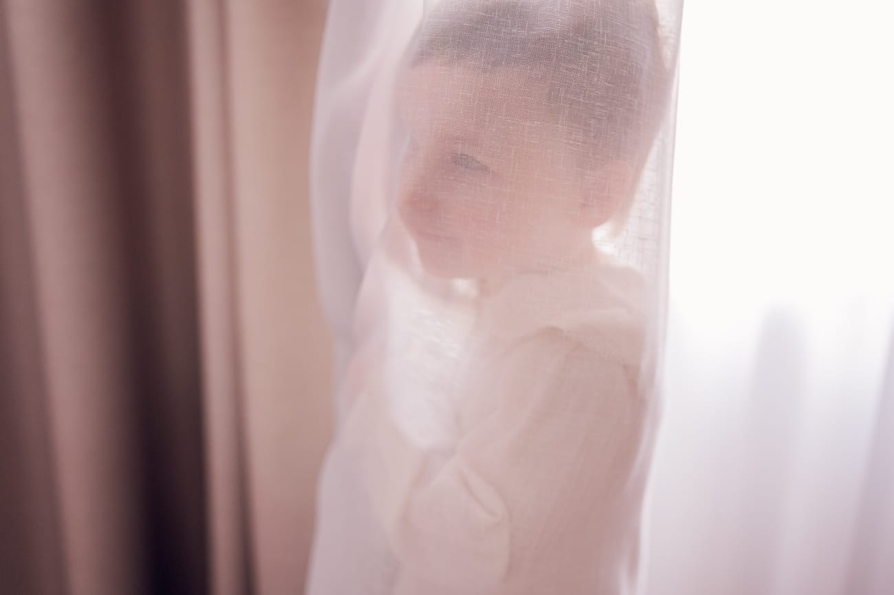 Dziecko chowające się za firanką w sypialni rodziców.