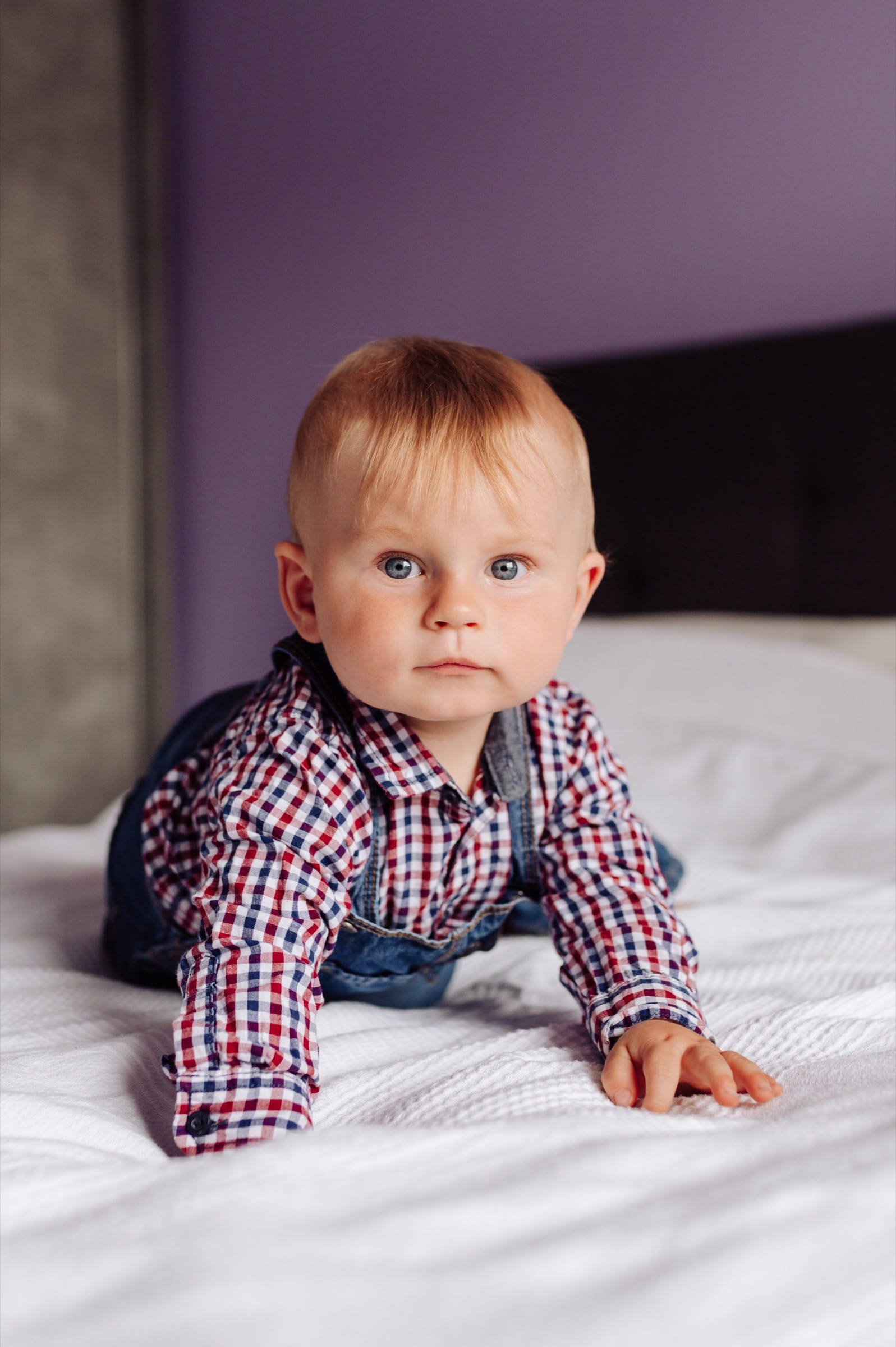 Chłopiec siedzący na łóżku podczas sesji rocznej — fotografia dziecięca Gdynia