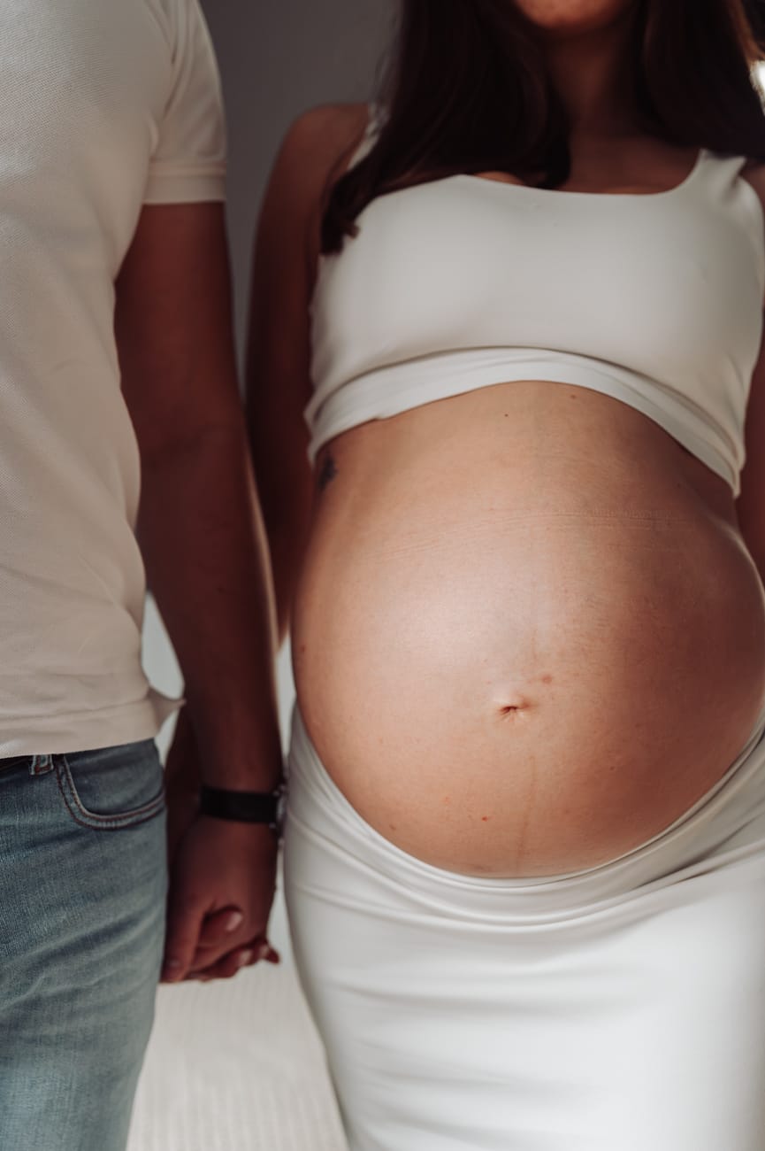 Zbliżenie dłoni i brzuszka ciążowego sesja ciążowa w domu