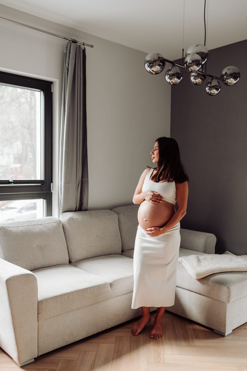 Mama w ciąży przy zasłonach sesja ciążowa w domu
