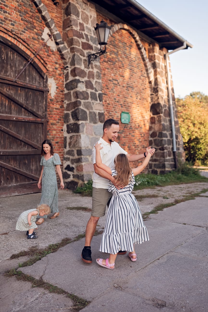 Tata tańczy z córką na tle starej stodoły sesja rodzinna w plenerze Gdynia
