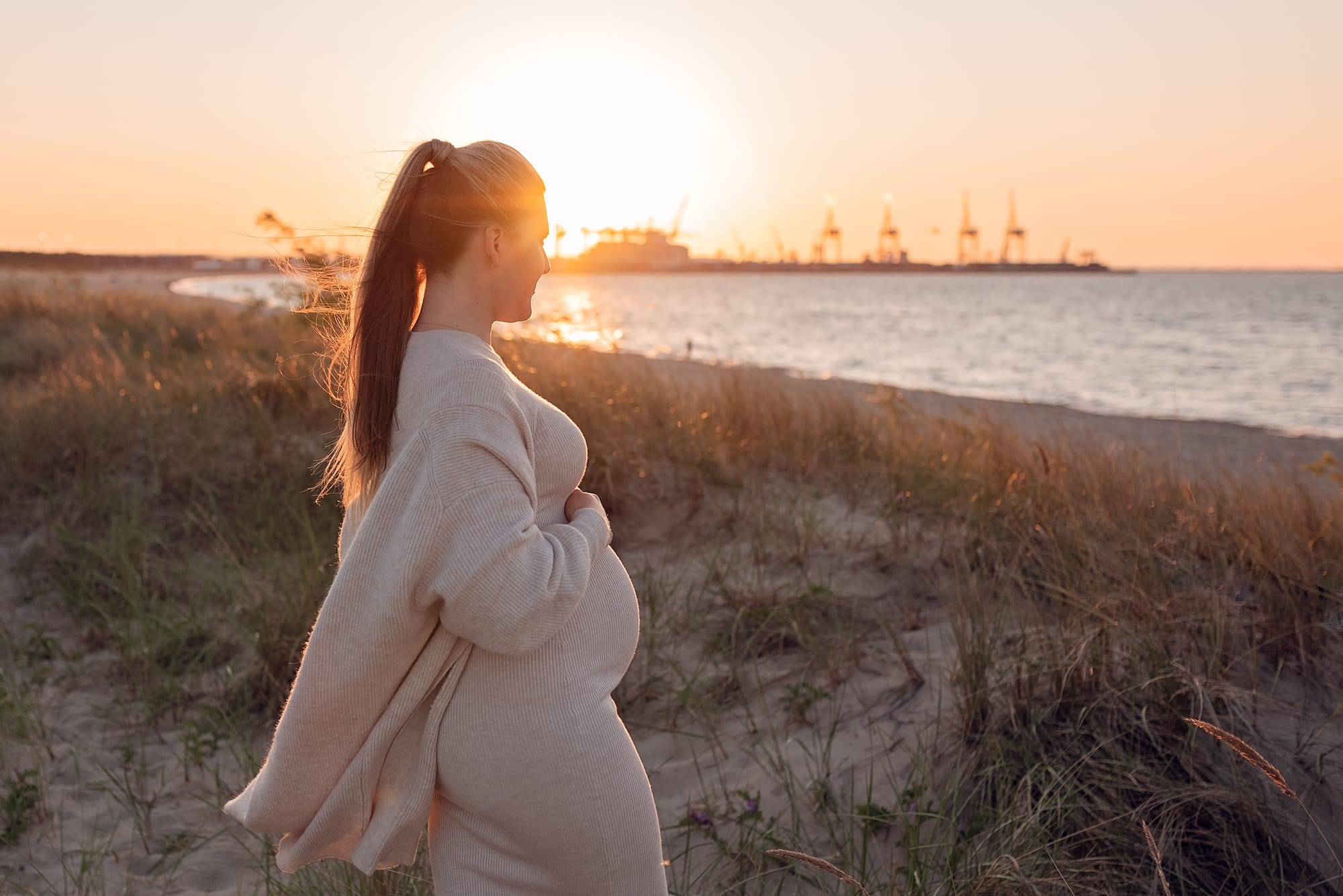Przyszła mama w ciąży nad morzem podczas zachodu słońca — sesja ciążowa w Trójmieście