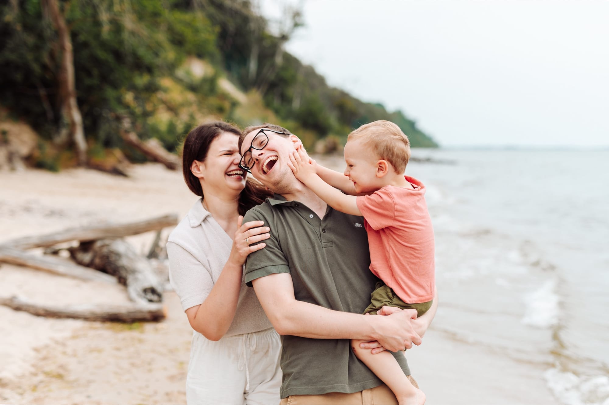 Rodzina z chłopcem na rękach, który odpycha tatę — wszyscy się śmieją, sesja rodzinna Babie Doły