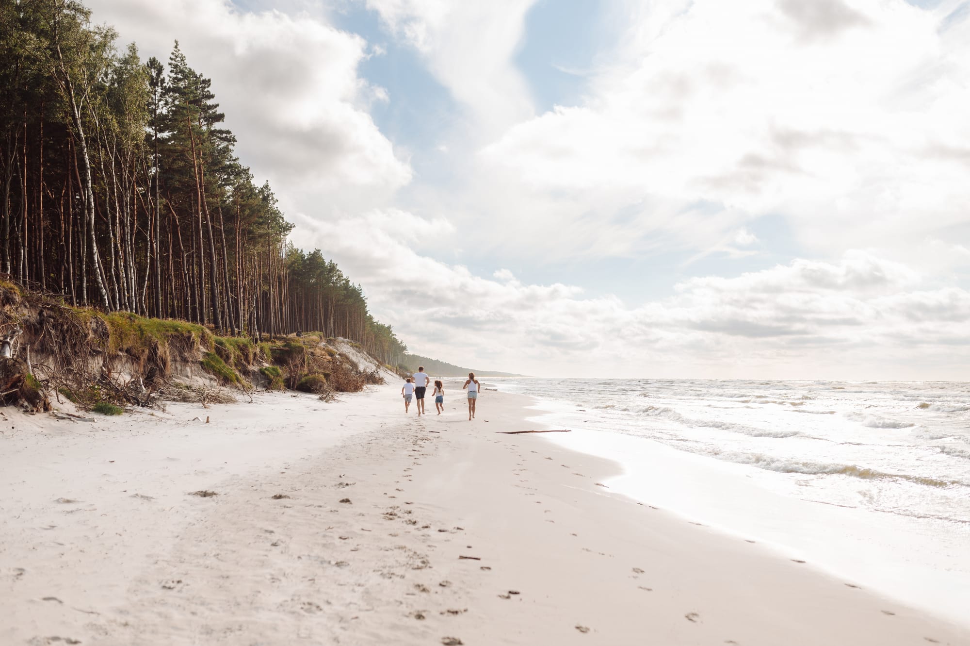 Rodzina biegnąca wzdłuż plaży podczas sesji fotograficznej nad morzem