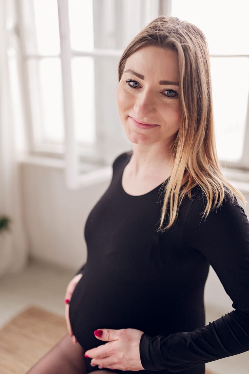 Mama w ciąży przy oknie sesja w studio Gdańsk