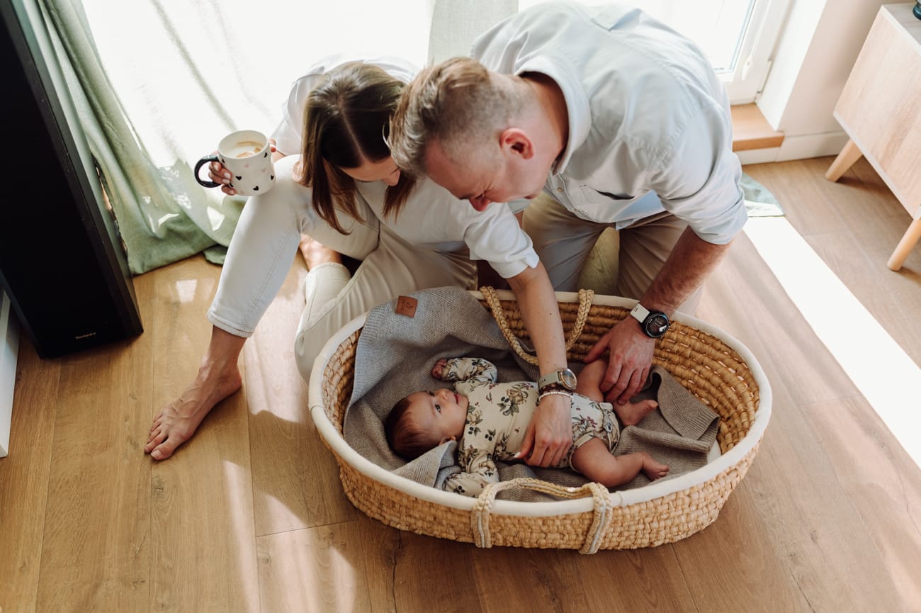 Rodzice nachylają się nad niemowlakiem naturalna sesja rodzinna Gdańsk