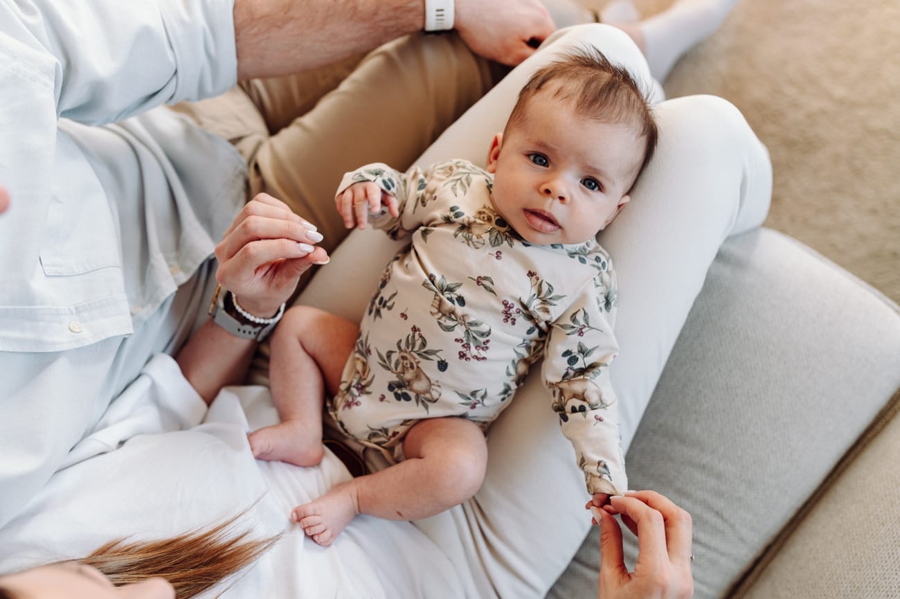 Niemowlak wpatrzony w obiektyw na kolanach mamy sesja niemowlęca lifestyle Gdańsk