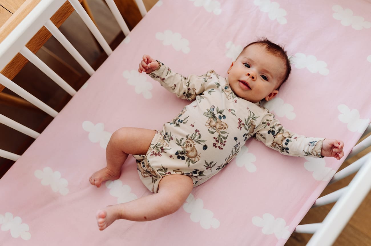 Zrelaksowane niemowle wpatrzone w obiektyw sesja domowa lifestyle Trójmiasto