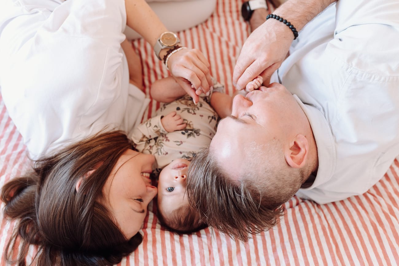Rodzice całujący niemowlaka - sesja rodzinna lifestyle Gdańsk