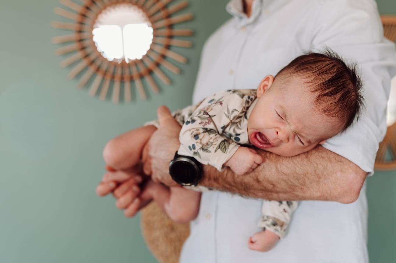 Mama trzyma ziewającego niemowlaka na rękach — domowa sesja niemowlęca Gdańsk