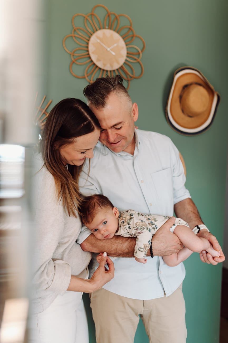 Rodzice trzymają niemowlaka — naturalna fotografia rodzinna Gdańsk