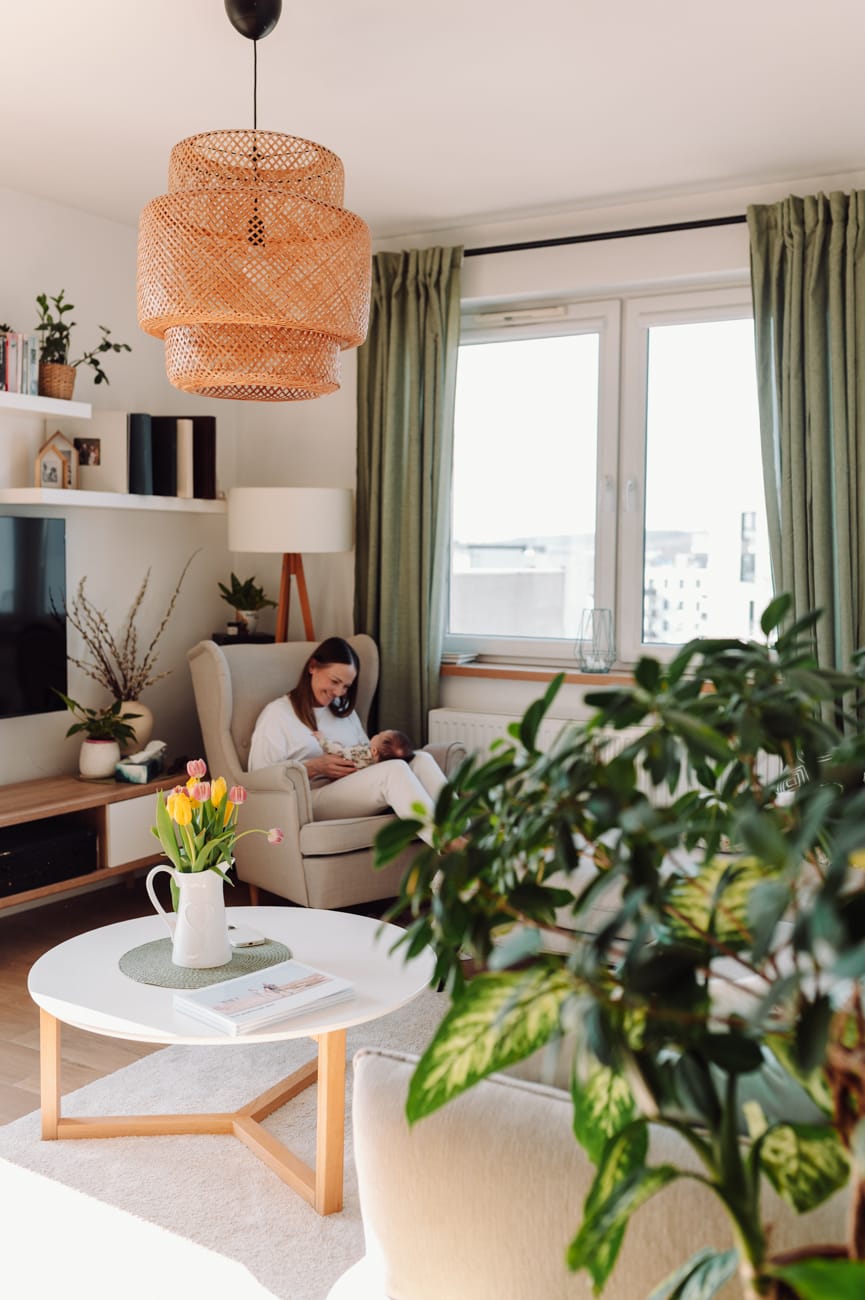 Mama wpatrująca się w swoją córeczkę - naturalne zdjęcia niemowlaka w domu