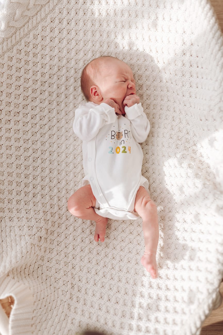 Noworodek ssie piąstkę w koszu sesja noworodkowa w domu Gdynia