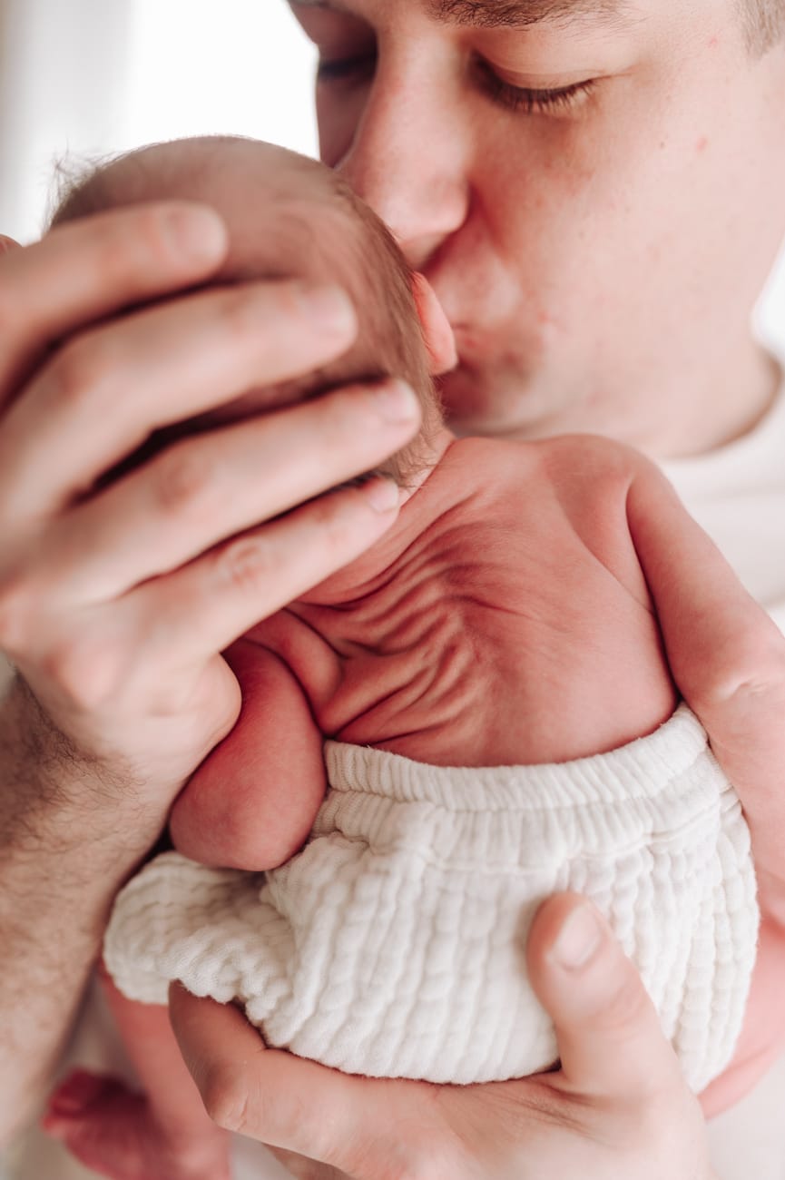 Tata całuje noworodka sesja noworodkowa w domu Gdynia