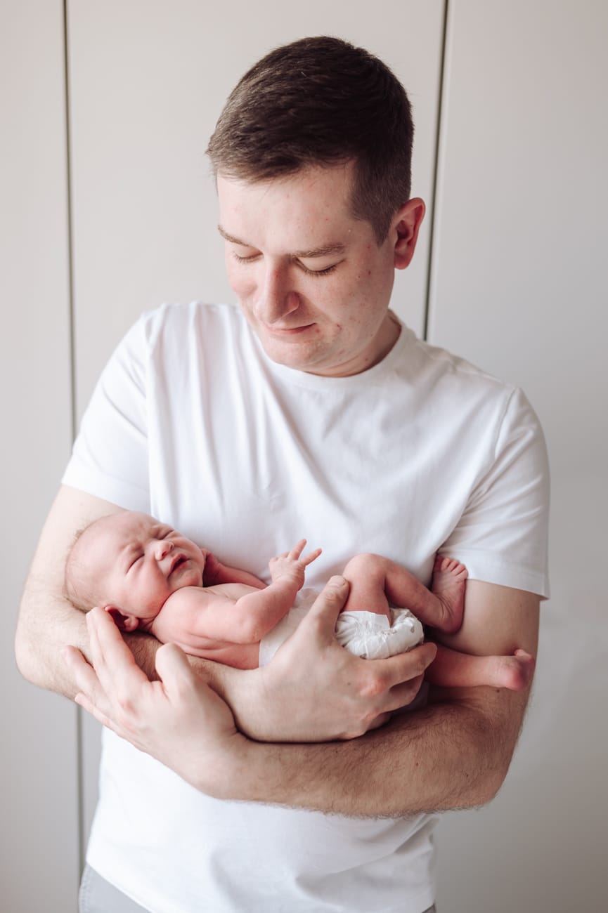Śpiący noworodek w ramionach taty sesja w domu Gdynia