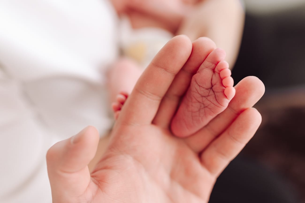Stópka noworodka w palcach taty detal sesja w domu Gdynia