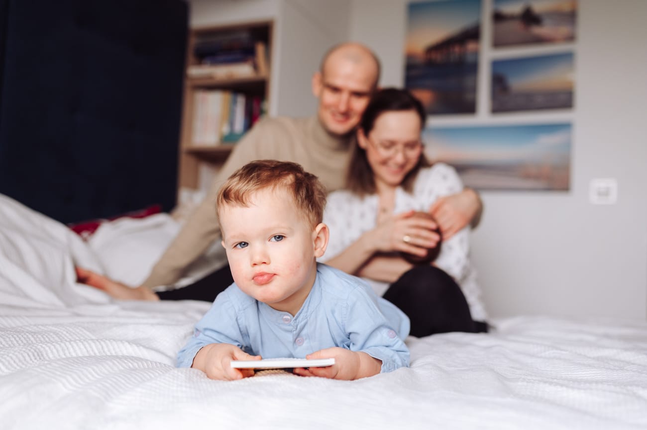 Starszak a w tle rodzice z noworodkiem sesja Gdynia