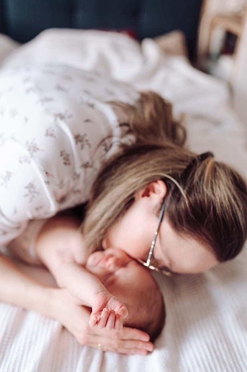 Mama całuje noworodka sesja rodzinna w domu