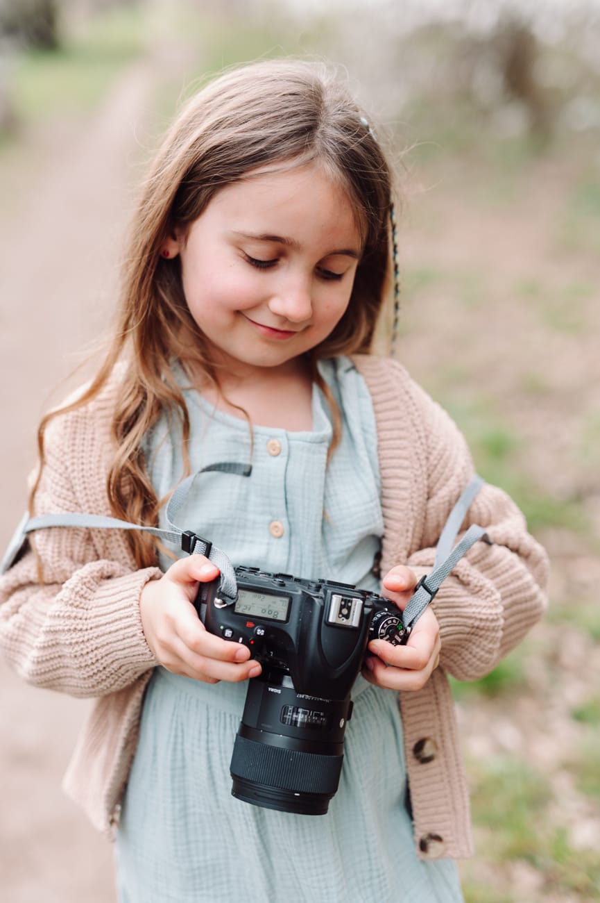 Dziewczynka trzyma aparat sesja dziecięca w plenerze