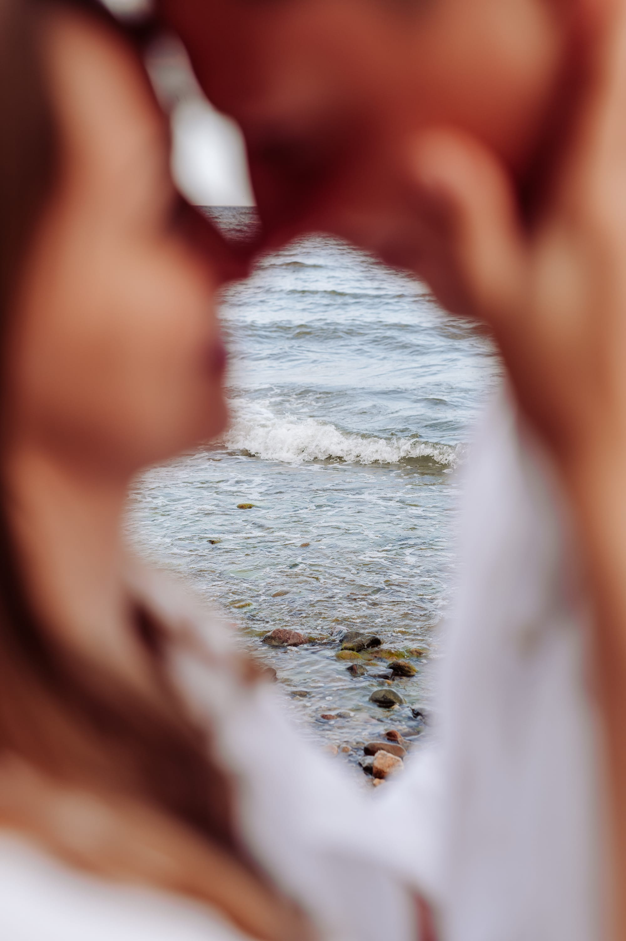 Przyszli rodzice patrzą sobie w oczy, wyostrzone morze w tle — sesja ciążowa Orłowo Gdynia, fotograf Natalia Kobylak