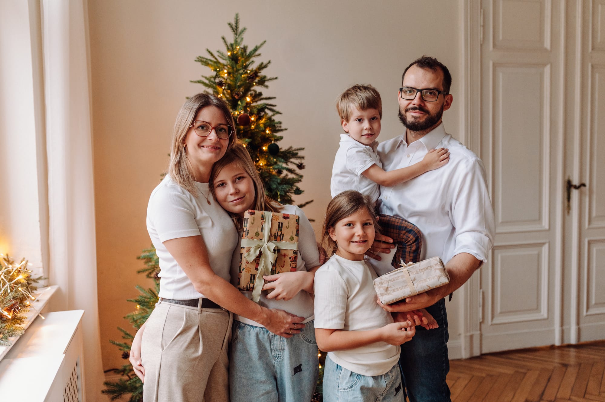 Rodzina pozująca pod choinką z prezentami w dłoniach, sesja świąteczna w studio Wrzeszcz