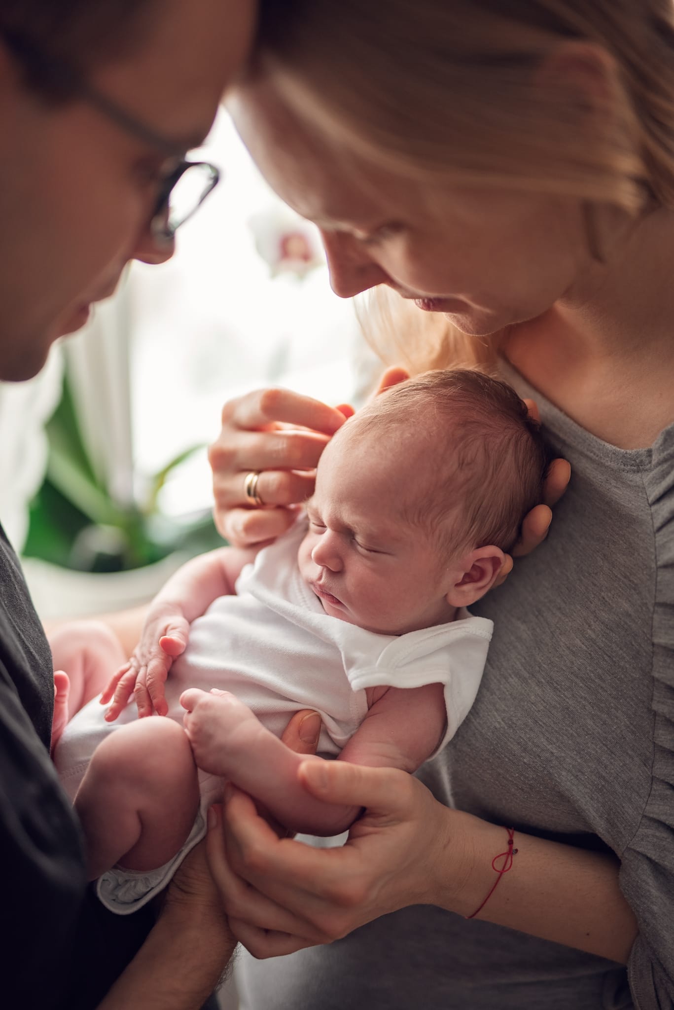 Rodzice stykają się czołami noworodek między nimi sesja w domu