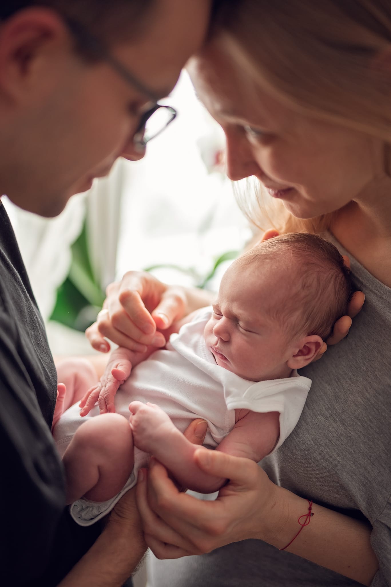 Rodzice stykają się czołami noworodek między nimi sesja lifestyle