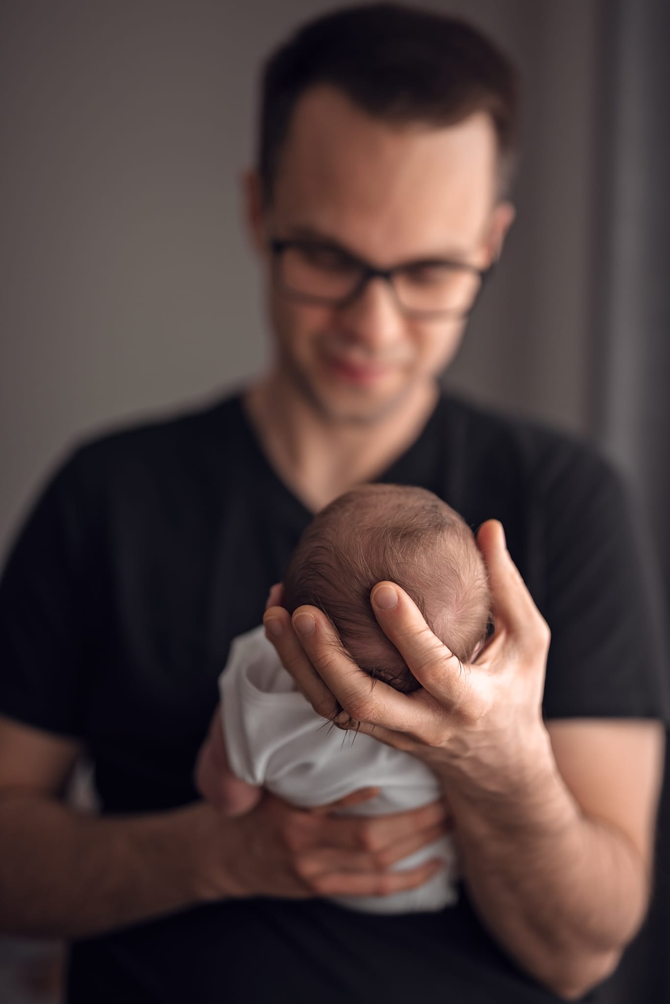 Tata trzyma noworodka w dłoniach sesja w domu