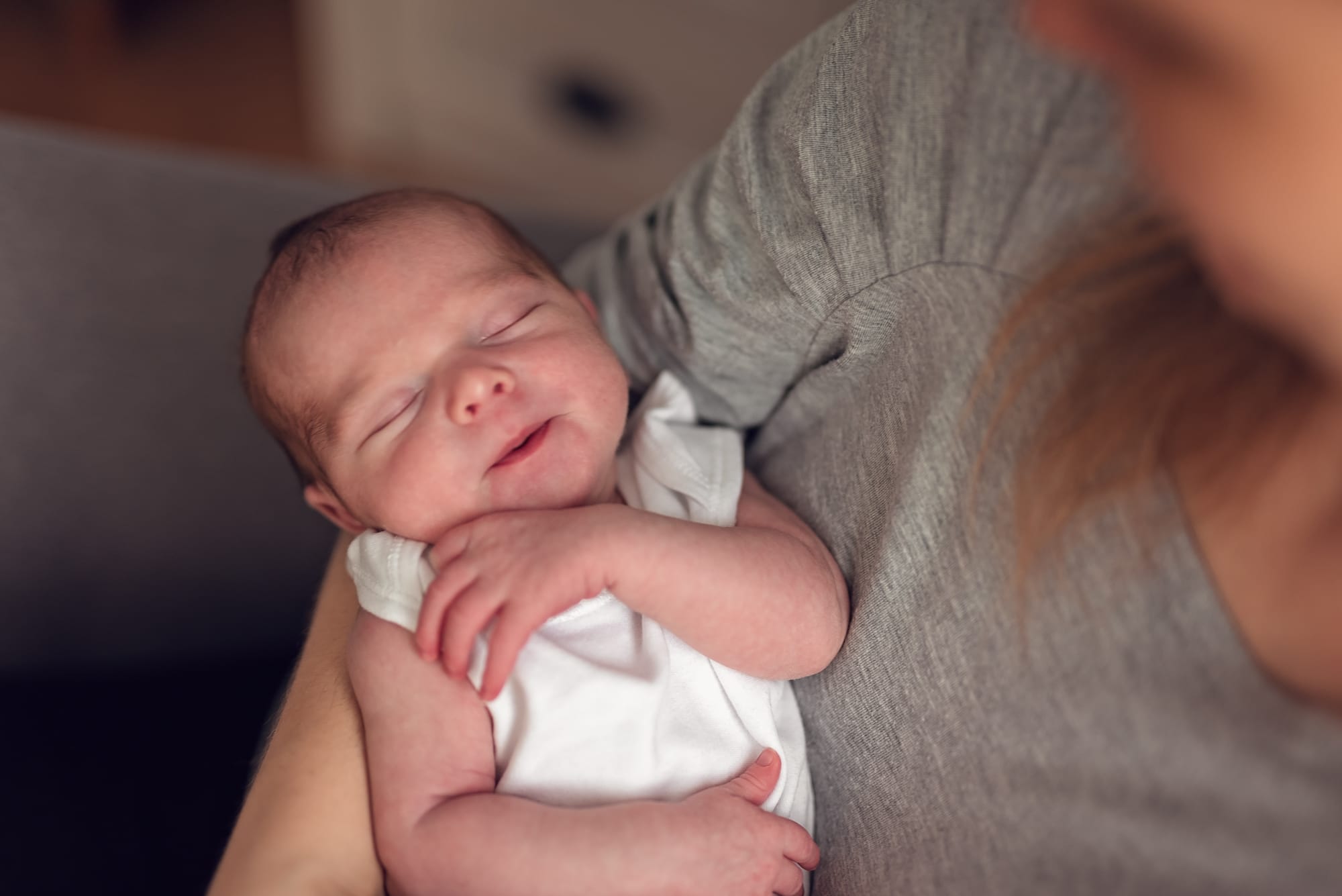 Mama z noworodkiem na łóżku jasna pościel sesja w domu