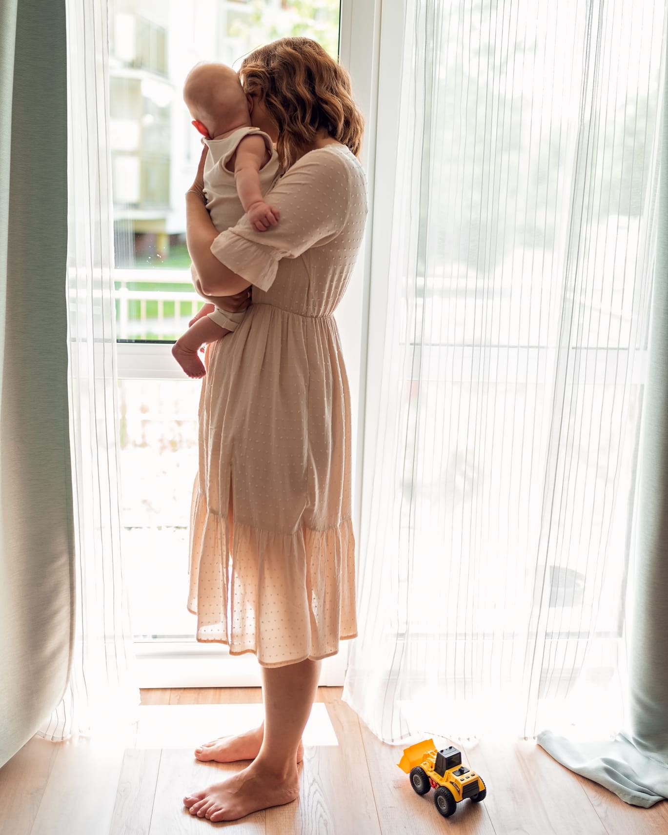 Mama z synkiem na rękach przy oknie a obok autko sesja rodzinna w domu