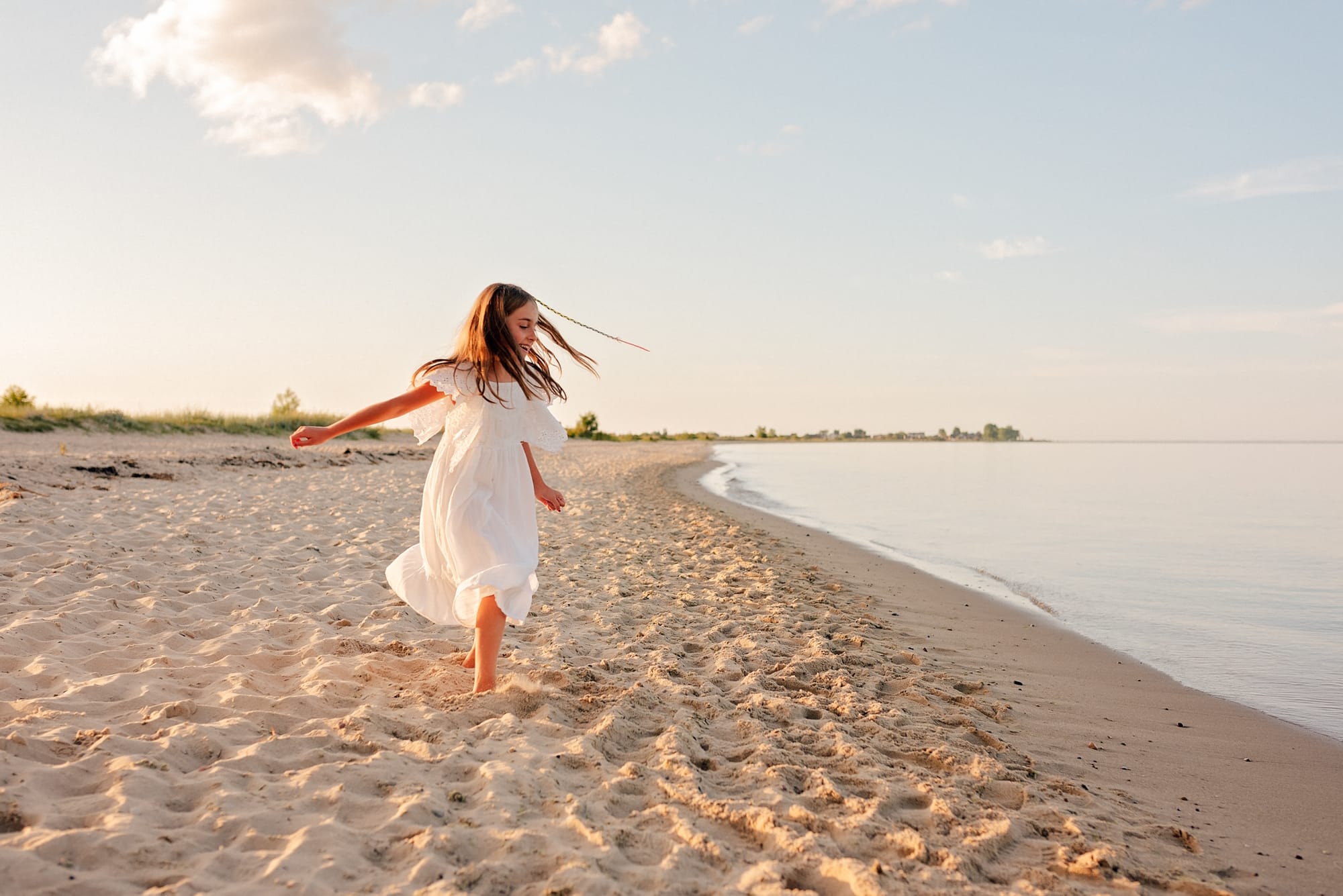 Dziewczynka tańcząca na pustej plaży o zachodzie słońca.