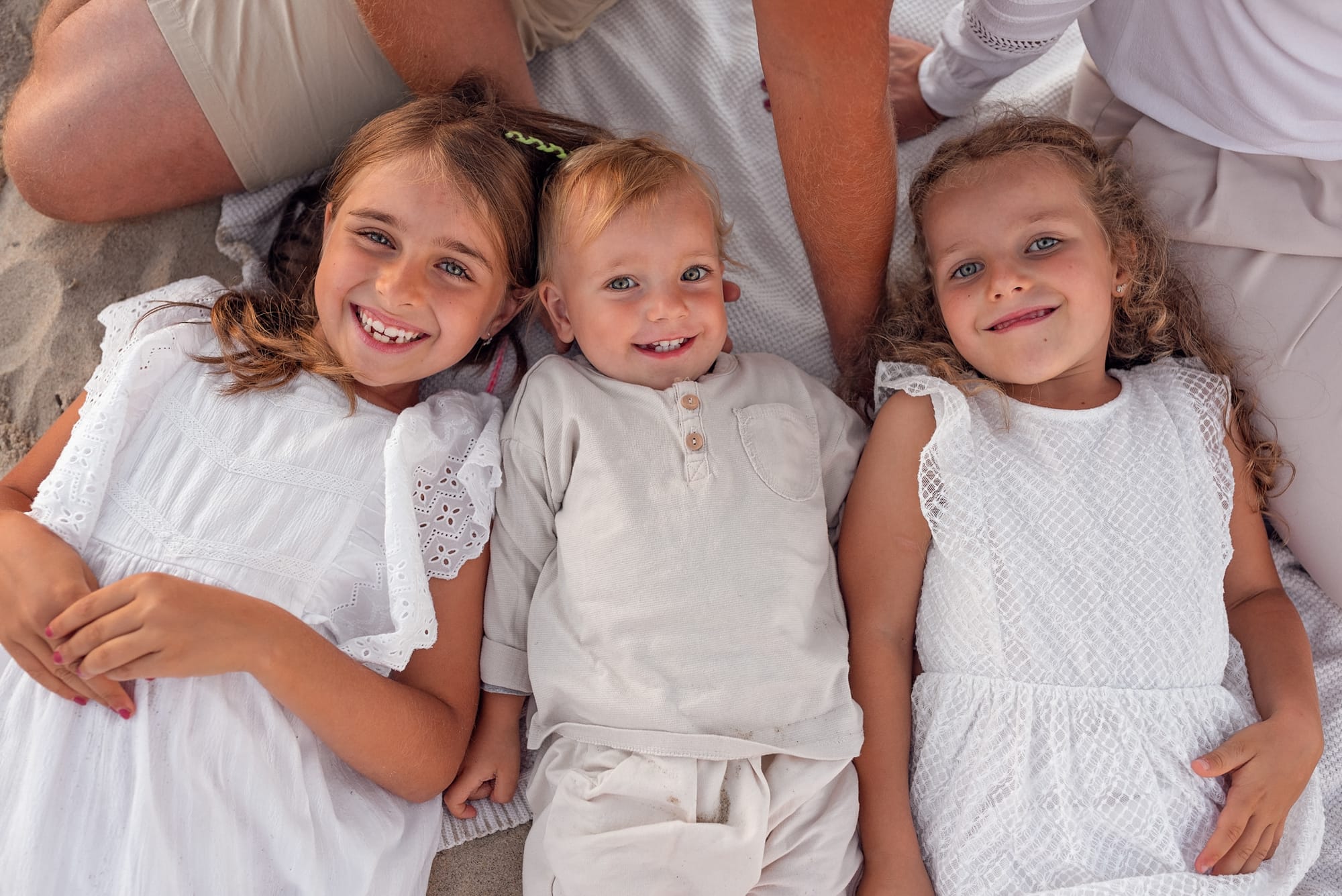 Portret rodzeństwa leżącego na plaży podczas rodzinnej. sesji.