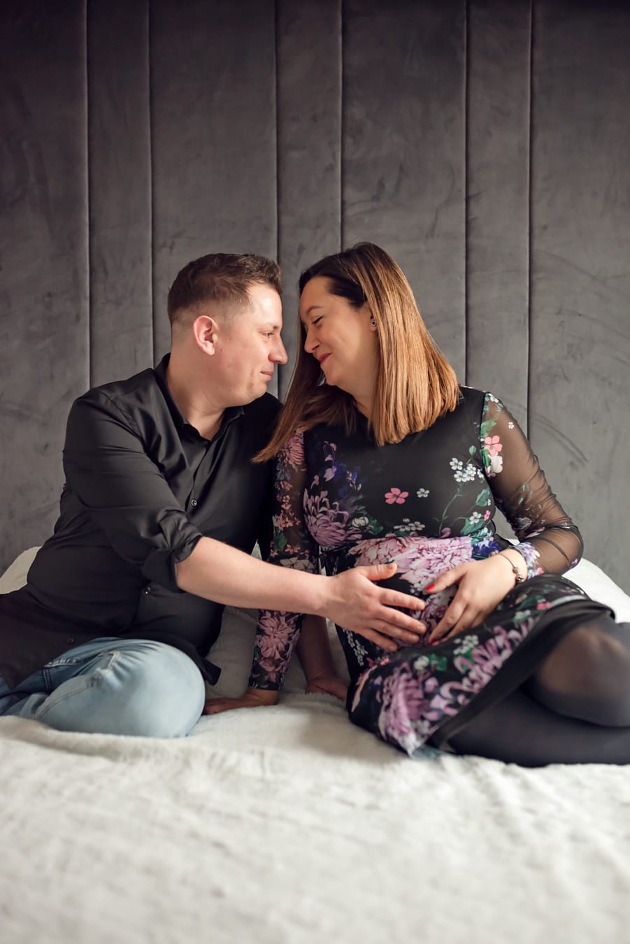 Para na łóżku dotyka brzuszka sesja ciążowa w domu