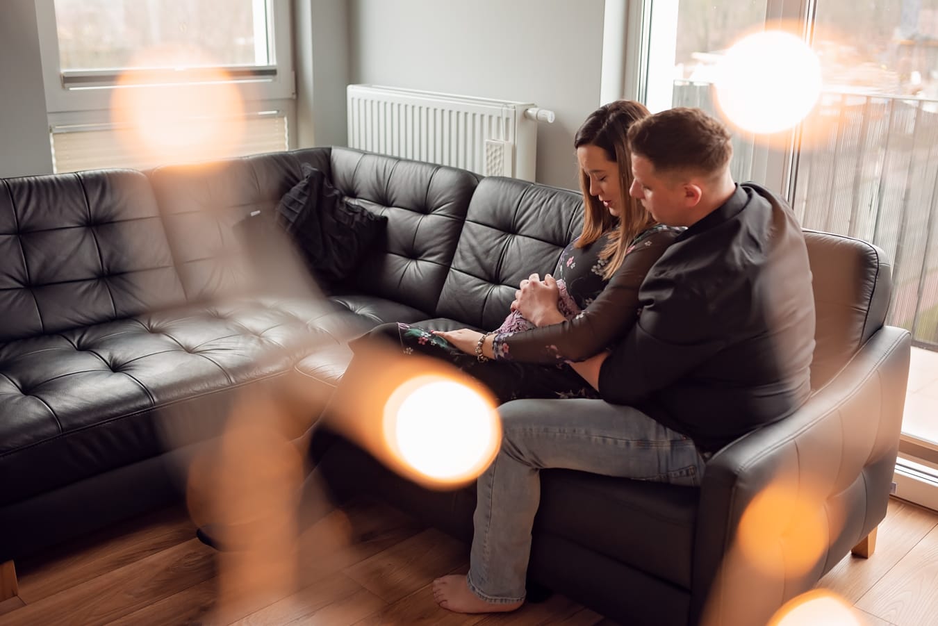 Para na kanapie głaszcze brzuszek sesja ciążowa