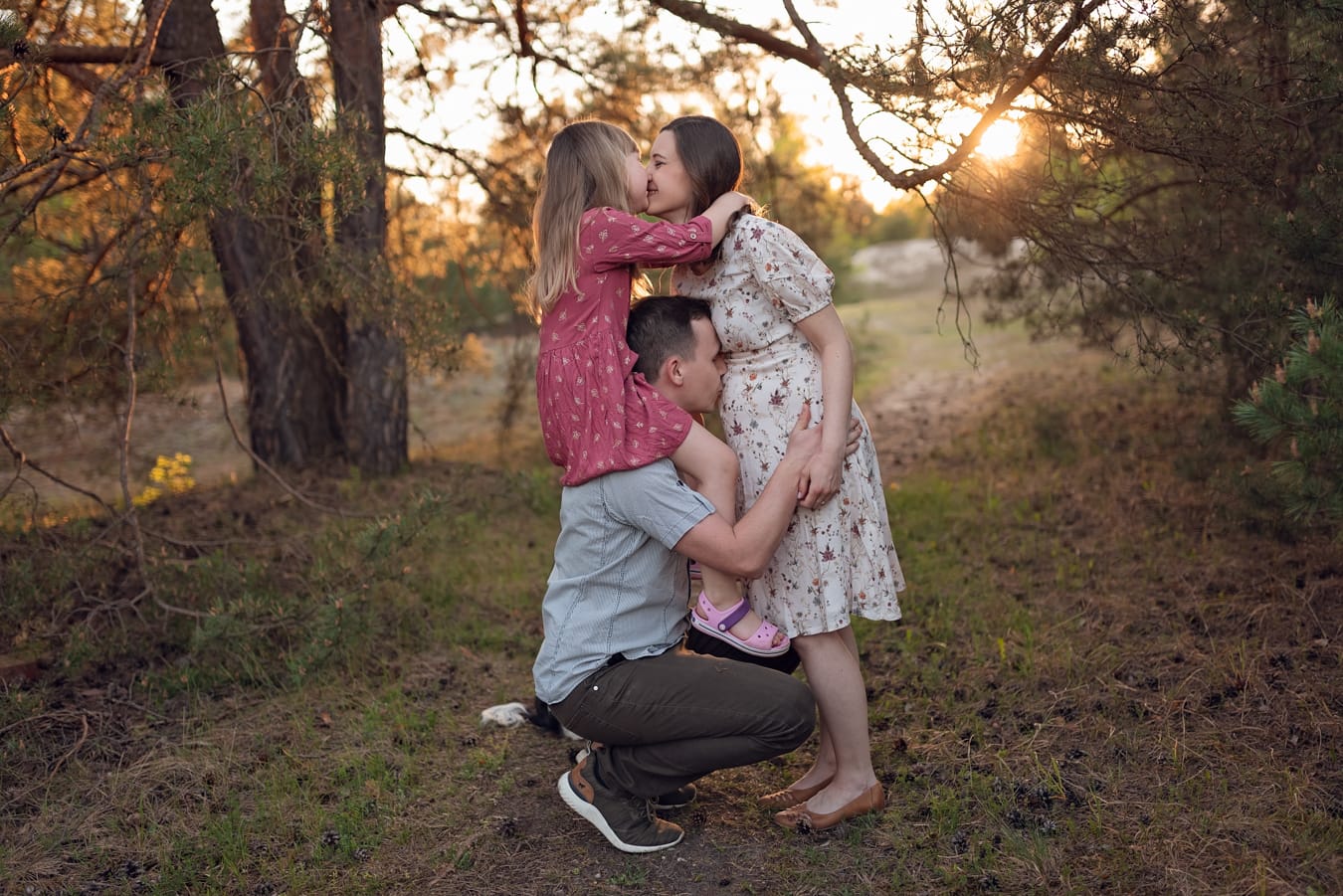Mama całuje córkę tata całuje brzuszek sesja ciążowa
