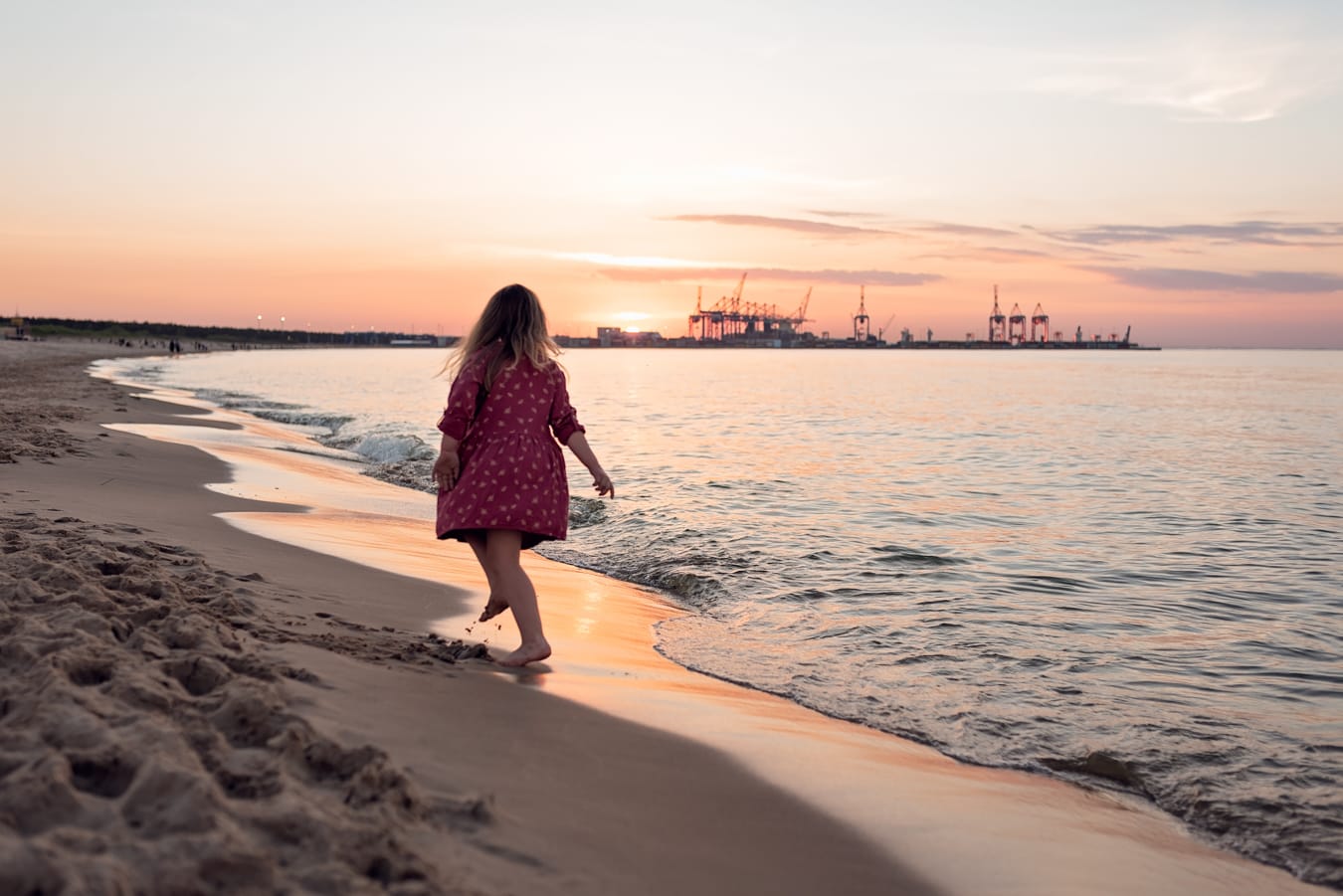 Tańcząca dziewczynka na brzegu morza zachód słońca sesja ciążowa