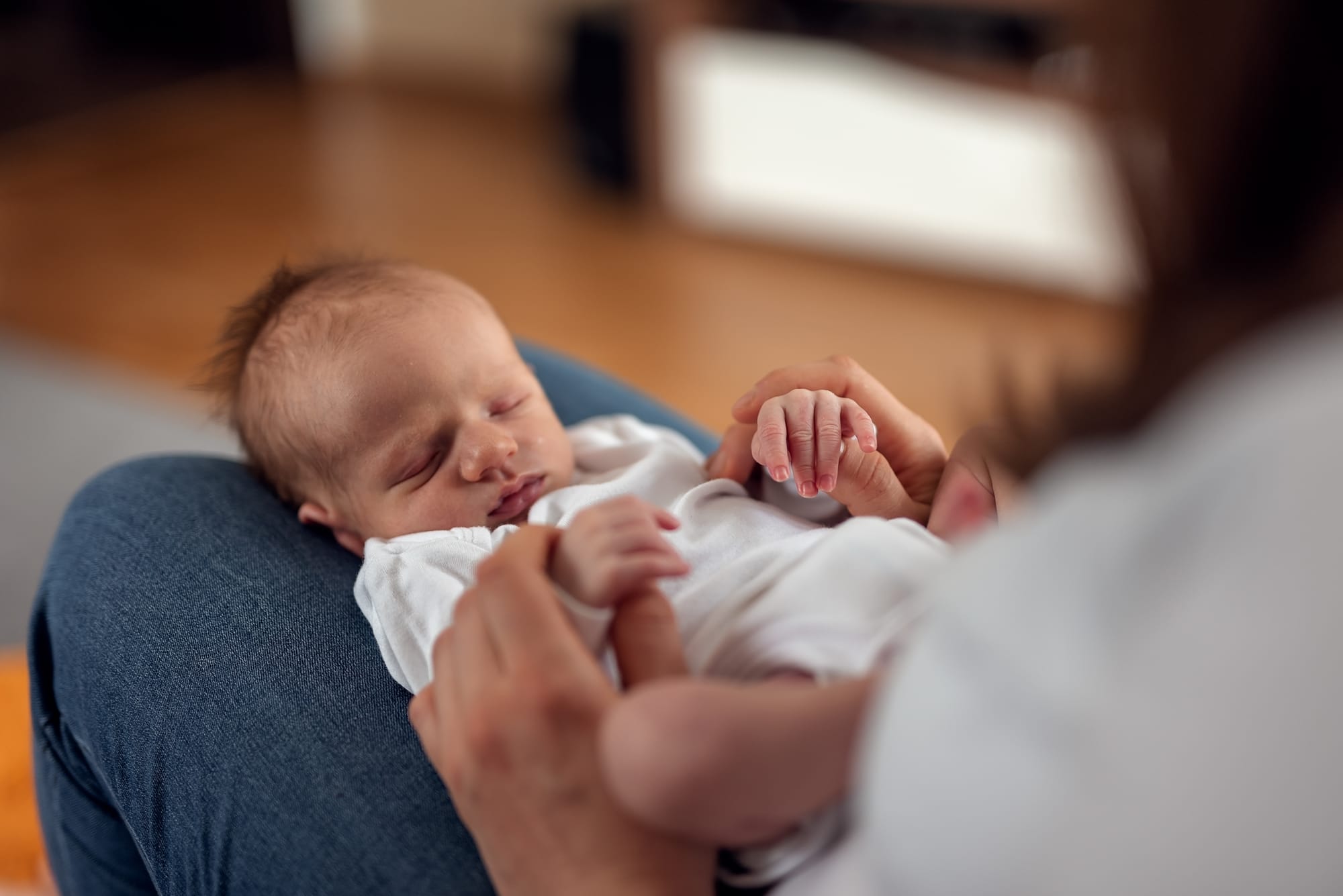 Noworodek na kolanach mamy sesja noworodkowa w domu
