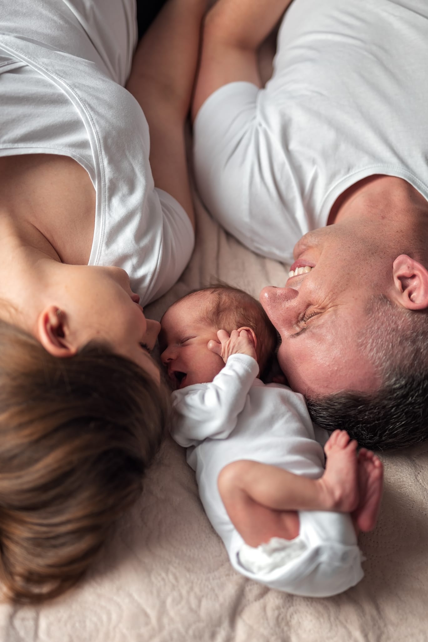 Rodzice z noworodkiem na łóżku sesja noworodkowa w domu