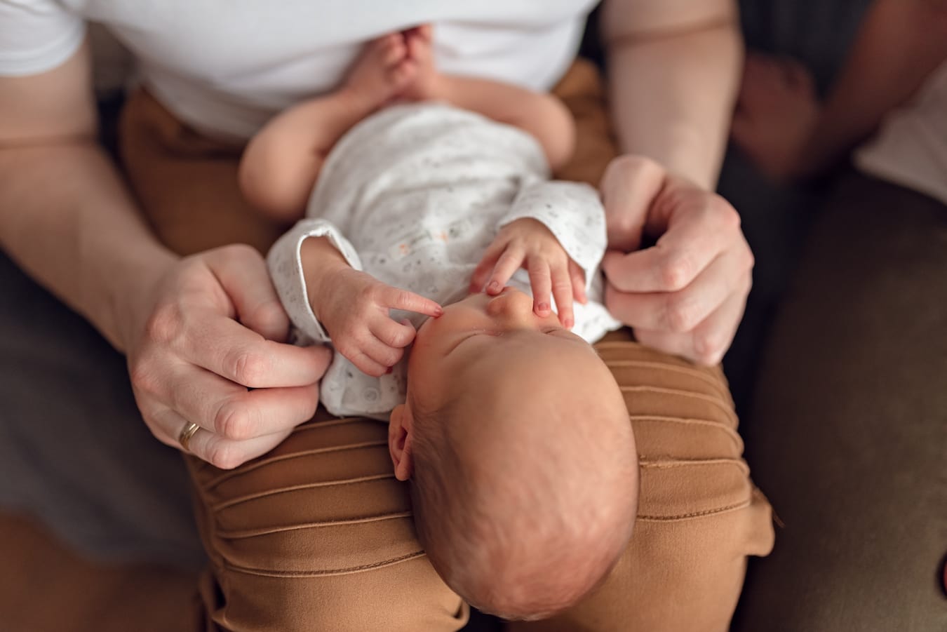 Główka noworodka na kolanach taty sesja w domu Gdańsk