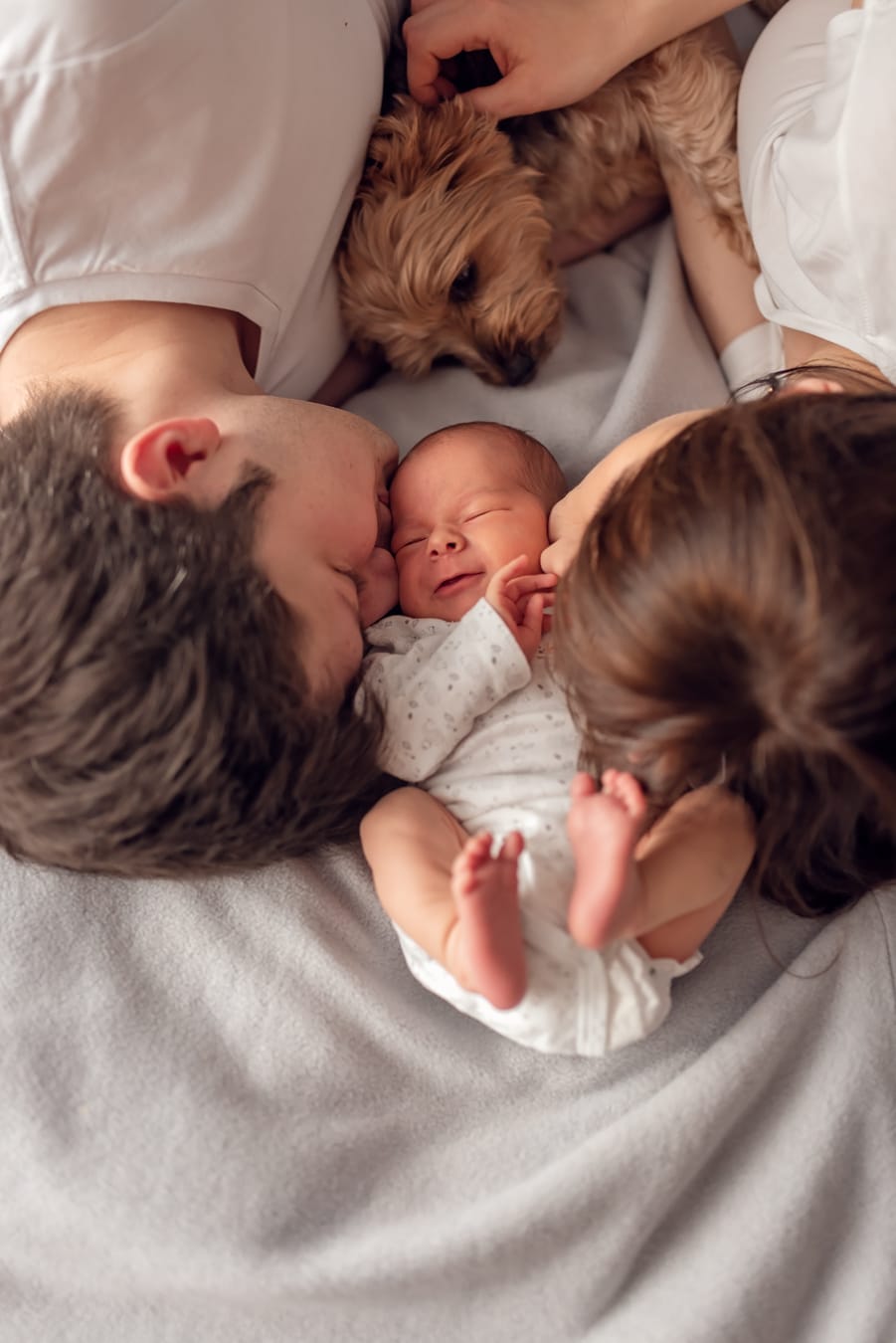 Rodzice całują noworodka pies obok sesja w domu Gdańsk