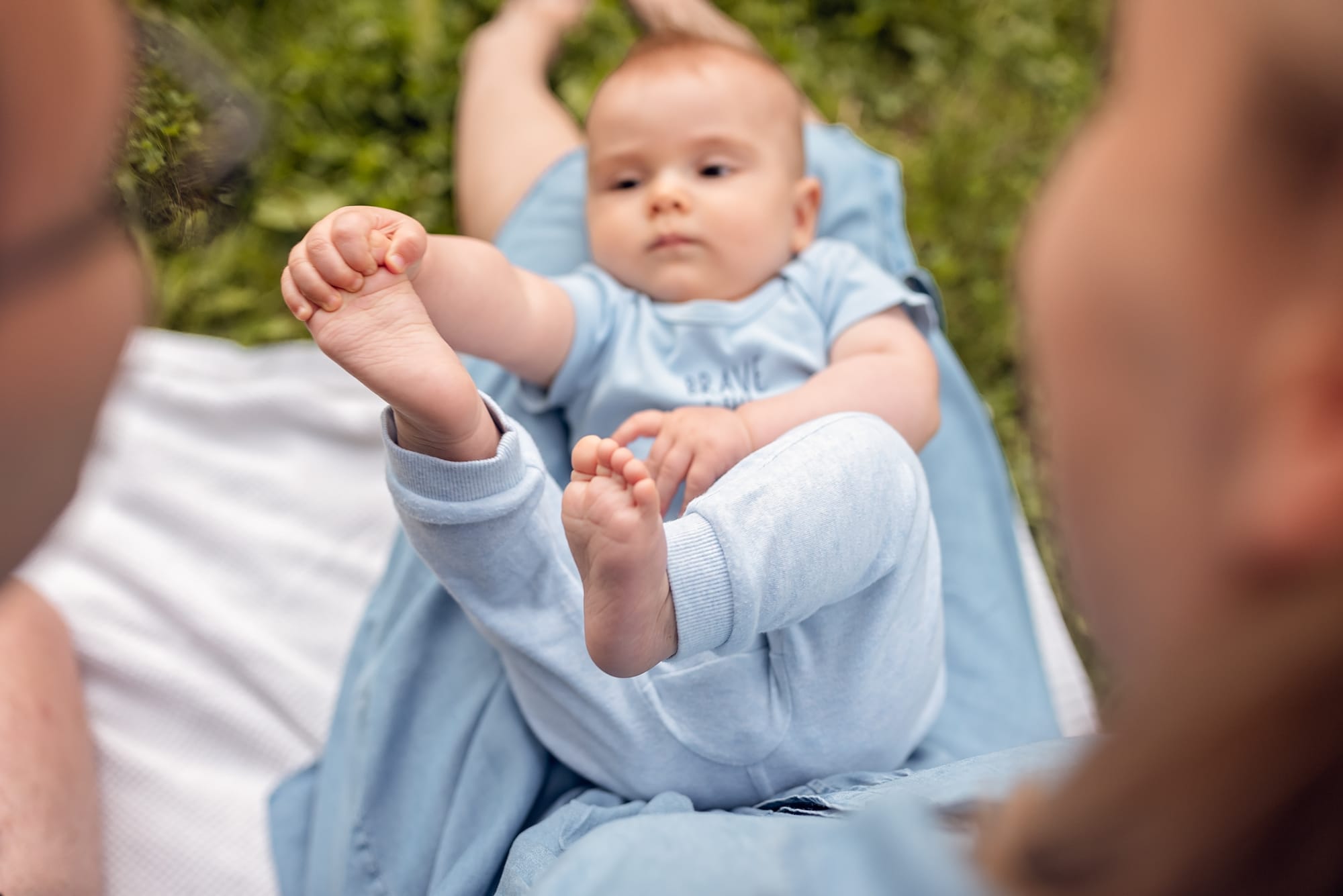 Niemowlak bawi się stópkami sesja z niemowlakiem w plenerze