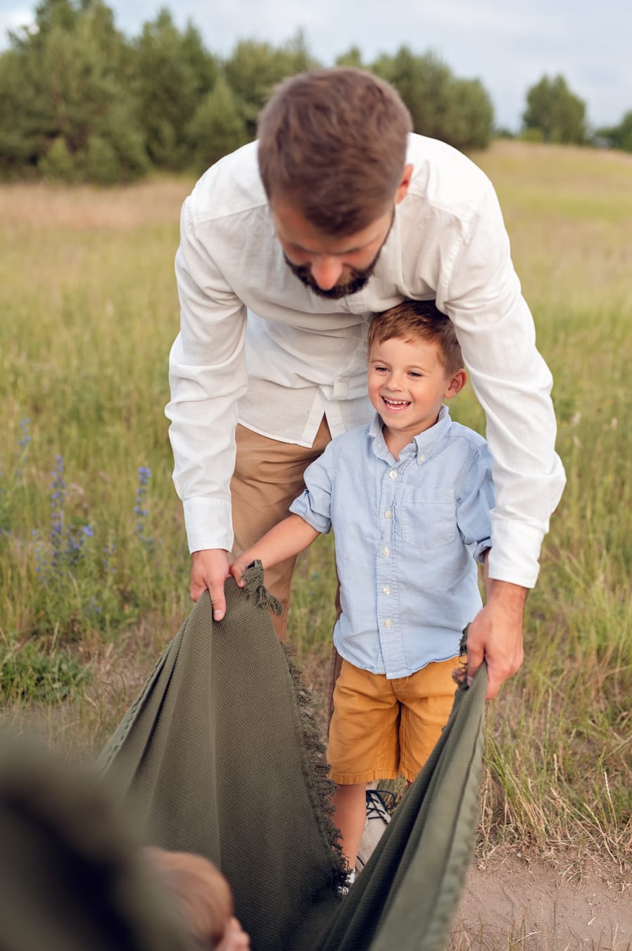 Tata z synem bujają brata w kocu sesja rodzinna