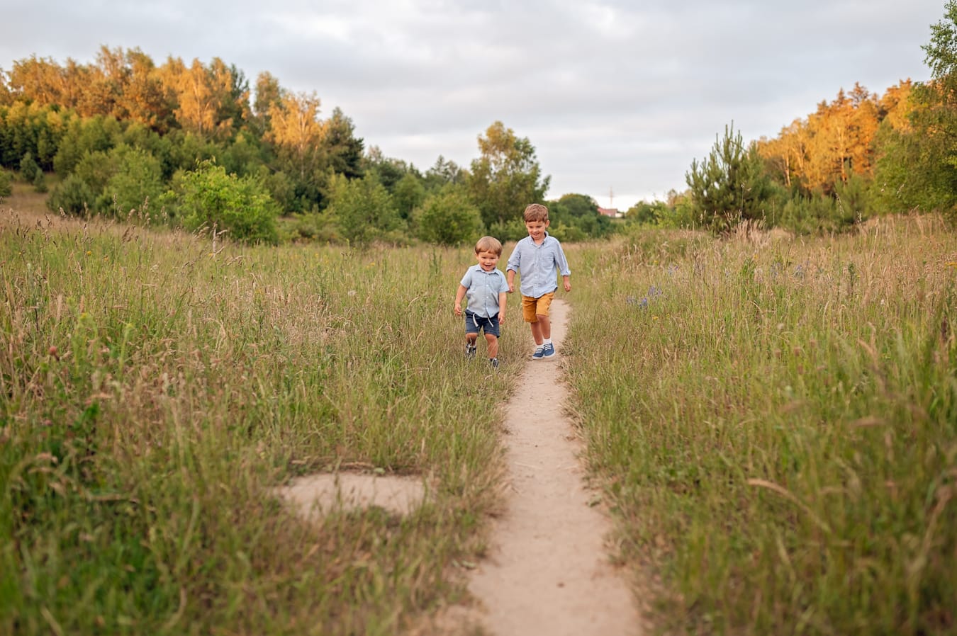 Chłopcy biegną po łące sesja rodzinna w plenerze