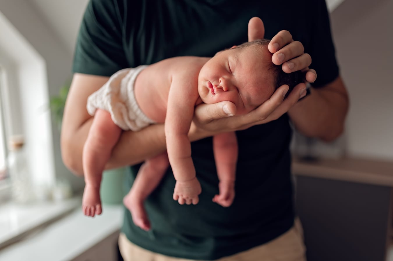 Tata głaszcze noworodka sesja lifestyle w domu Gdańsk