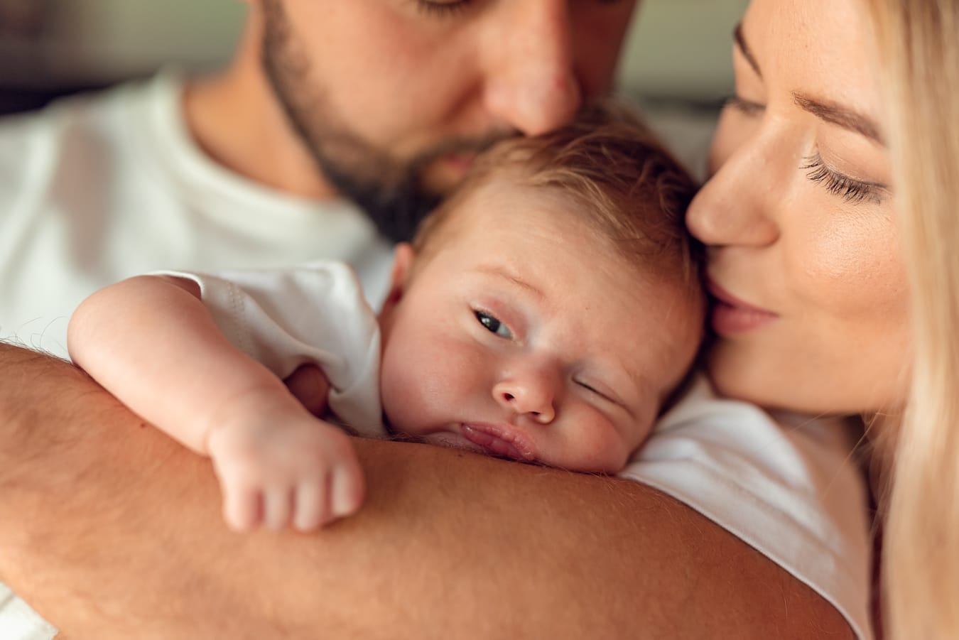 Mama całuje niemowlę na rękach taty sesja w domu